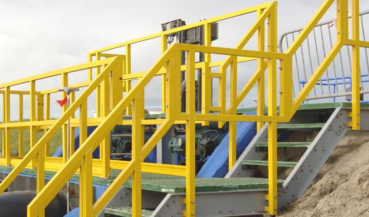 Système d'escalier FRP/GRP avec mains courantes jaunes, poutres grises et marches d'escalier vertes.